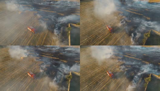 消防车在烟雾缭绕的干燥的残茬火焰中，消防员用水管灭火高清在线视频素材下载
