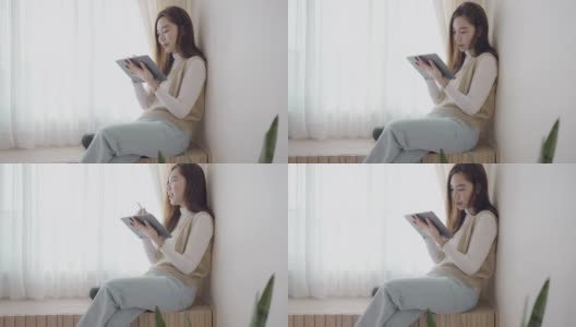 年轻的亚洲女性在家里用数码平板电脑工作高清在线视频素材下载