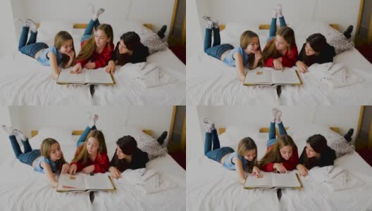 三个快乐的姐妹躺在卧室里看书。高清在线视频素材下载