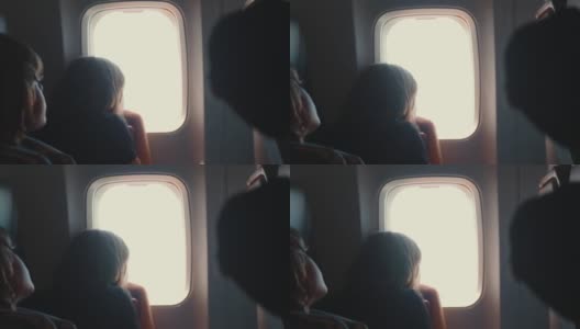 两个快乐的十几岁的乘客孩子，男孩和女孩在飞机上看着窗外的座位上的美景高清在线视频素材下载