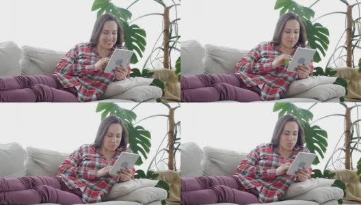 无忧无虑的女人一边吃苹果一边用平板电脑上网高清在线视频素材下载