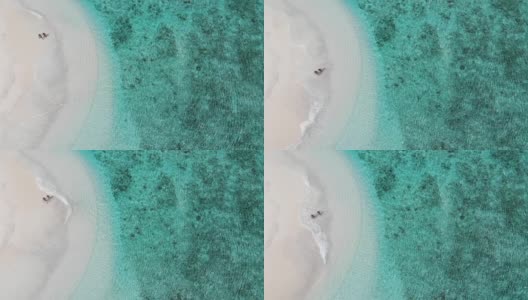 无人机拍摄的情侣在美丽的沙滩上行走的视频。航拍的男人和女人手牵手在沙滩上，印度洋，马尔代夫。水位上升的孤岛旅游目的地。高清在线视频素材下载