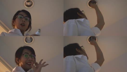 一个亚洲女人在房间里换灯泡，高清在线视频素材下载