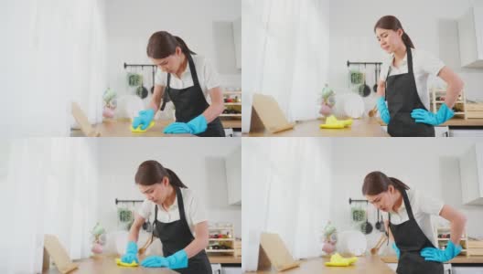 亚洲年轻清洁服务女工清洁厨房桌子在家里。年轻的女管家清洁工感到沮丧，而擦拭脏乱的烹饪柜台家务或杂务。高清在线视频素材下载