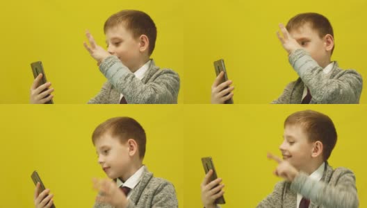 7-8岁的白人男孩穿着夹克在自拍，一个孩子在智能手机前摆姿势。这名男生拍了张照片留念。工作室拍摄。学龄儿童与新技术高清在线视频素材下载