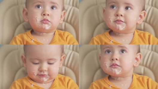 12-18个月大的蹒跚学步的孩子吃麦片粥时，会翻盘子。吃东西的时候又脏又搞笑的娃娃脸高清在线视频素材下载