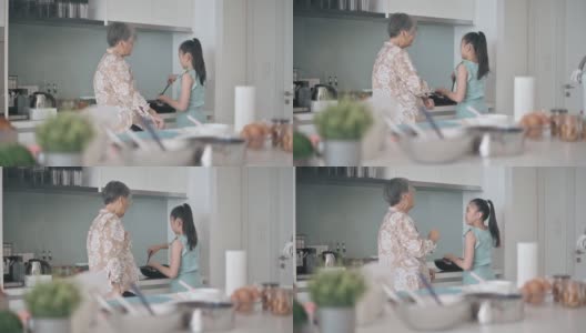 亚裔中国孙女在周末闲暇时间在厨房里跟奶奶学习烹饪技巧高清在线视频素材下载