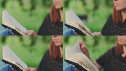 一个女人拿着一本书坐在公园的一棵树旁。一个穿着牛仔裤和t恤的女人在户外看书。高清在线视频素材下载