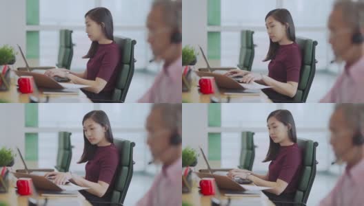 亚裔中国美女在办公室用笔记本电脑在同事旁边打字高清在线视频素材下载