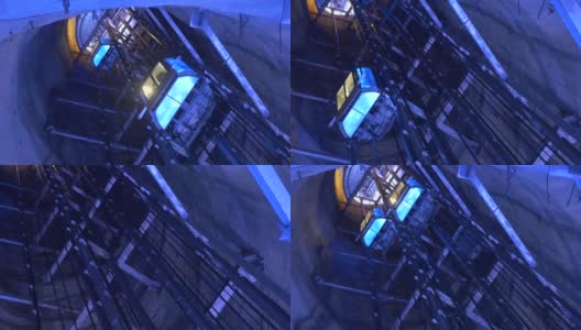 通过深井上下的人乘坐的电梯被蓝色的94p2灯照亮高清在线视频素材下载