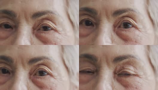 白发苍苍的亚洲老年女性(80岁)用眼睛直视镜头，近距离观察脸部和眼睛，脸上布满皱纹，洋溢着享受退休生活的快乐。高清在线视频素材下载
