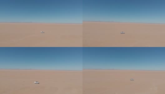 无人机航拍的视频画面显示，一辆白色四驱车吉普车驶过非洲纳米比亚的沙漠。一辆白色轿车孤立地开向远方。越野和超载的背包探险旅行。无人机跟随吉普车探索沙漠。高清在线视频素材下载