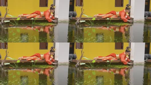 身着红旗袍的女子在池塘边休息高清在线视频素材下载