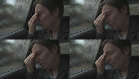 女商人，下雨天坐在汽车后座，头痛得厉害高清在线视频素材下载