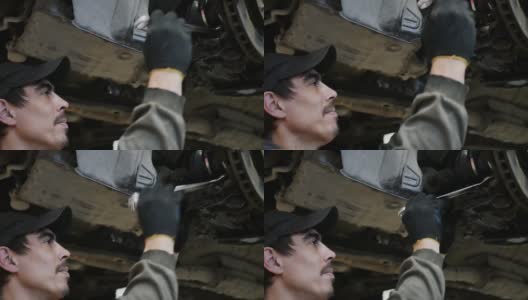 汽车下面的一个男性汽车修理工用扳手拧紧了螺母高清在线视频素材下载