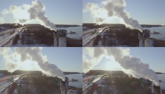 在一个阳光明媚的冬日里，瑞典斯堪的那维亚，发电厂的烟囱里飘着污染的烟雾，以火车和高速公路为背景发电高清在线视频素材下载