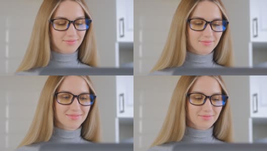 快乐的白人女人在电脑上工作。视频肖像的美丽的年轻成年女性长金发戴眼镜，在家里做远程工作的笔记本电脑在一级防范禁闭高清在线视频素材下载
