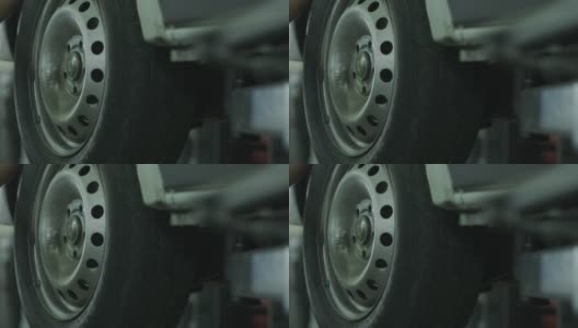 在服务站，汽车修理工拆卸了一个车轮，更换了一辆抬起的汽车车轮上的刹车片高清在线视频素材下载