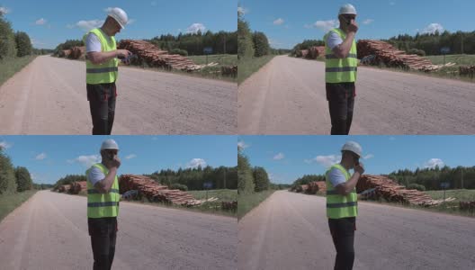 伐木工人在靠近木材堆的道路上使用平板电脑高清在线视频素材下载
