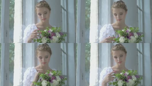 美丽的女孩穿着复古的白裙子坐在窗台上触摸鲜花，慢镜头高清在线视频素材下载