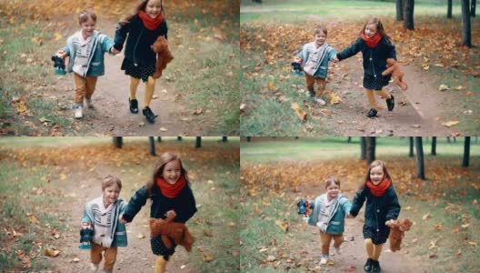 可爱的兄妹小男孩和小女孩手牵着手奔跑着，带着他们的玩具穿过秋天的公园慢莫胡同高清在线视频素材下载
