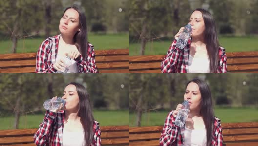 20多岁的年轻女孩在公园里喝瓶装水高清在线视频素材下载