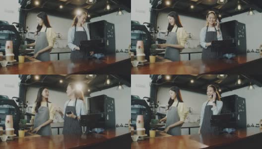 年轻美丽的亚洲女咖啡师穿着围裙在咖啡厅的柜台接受顾客的电话订购咖啡面带微笑。咖啡店和小型咖啡店的概念。高清在线视频素材下载