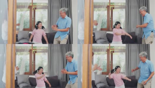 亚洲的祖父母和孙女在家一起听音乐和跳舞。中国老年人，爷爷和奶奶愉快地度过家庭时间和年轻女孩在客厅放松的概念。缓慢的运动。高清在线视频素材下载