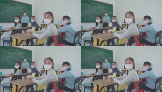 一群亚洲小学生和教师戴着卫生口罩在教室里防止Covid - 19的爆发，返校时重新开学，教育理念的新常态。高清在线视频素材下载