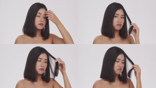 近距离的肖像沮丧的亚洲女人看着她受损的头发和噘嘴的嘴唇，白色的工作室背景高清在线视频素材下载