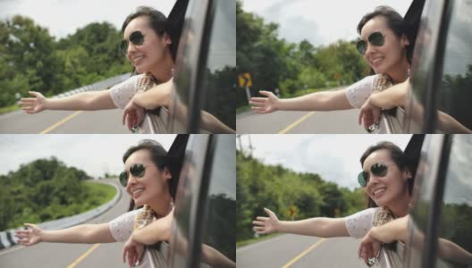 一个亚洲女人把她的手伸出车窗，笑了。慢动作高清在线视频素材下载