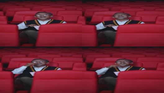 亚洲华人活跃的老人独自在电影院边看电影边吃零食高清在线视频素材下载