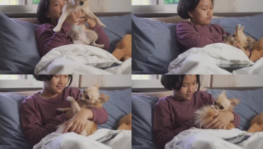 亚洲小孩在卧室里和狗玩。快乐的孩子在床上使用药片。高清在线视频素材下载