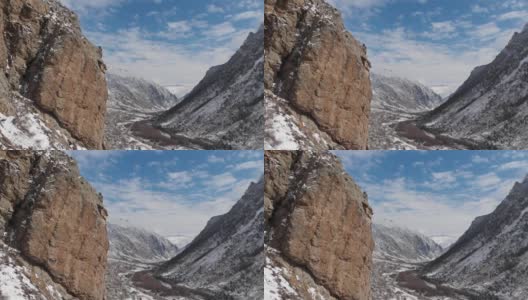 这是初春大雪纷飞的山峡岩石旁的跨度的鸟瞰图。高清在线视频素材下载