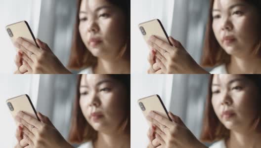 亚洲女人放松玩智能手机在客厅高清在线视频素材下载