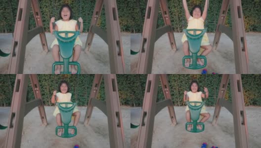 4K慢动作:亚洲可爱女孩快乐地在公共操场玩秋千。高清在线视频素材下载