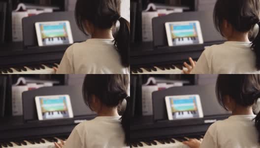 亚洲女孩正在学习和练习钢琴音乐使用在线平板电脑应用程序连接键盘使用蓝牙。高清在线视频素材下载