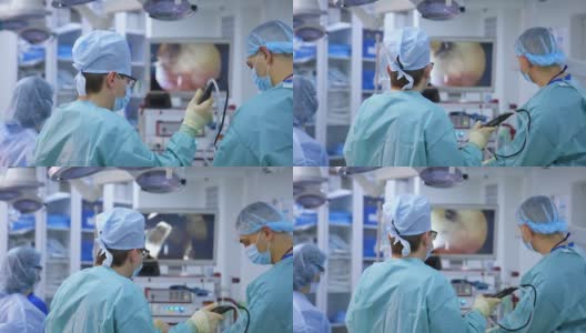 医疗团队背景上的大监视器。在现代化的手术室里，由专业的外科医生和助手进行外科手术。医生在医院外科手术中使用现代医疗设备。高清在线视频素材下载
