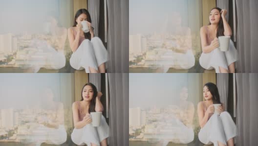 幸福迷人的亚洲女性放松休闲坐在窗边看外面手握热饮料在酒店房间高清在线视频素材下载