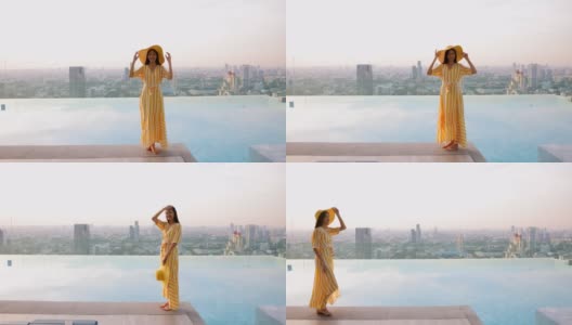 美丽的照片，亚洲妇女在一个黄色的长裙和黄色的大帽子走在池边在多彩的日落。女孩享受暑假与美丽的日落和城市的光线。高清在线视频素材下载