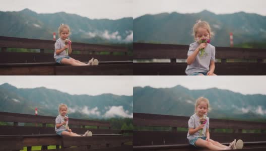 金发碧眼的孩子抱着野花坐在木凳上高清在线视频素材下载
