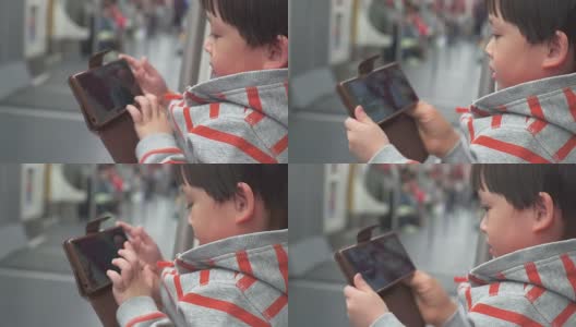 一个小男孩坐在火车上玩移动设备。高清在线视频素材下载