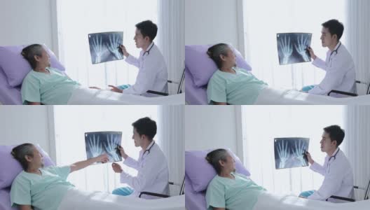 亚洲男医生手握骨x光片与患者交谈，讲解治疗方法，鼓励亚洲男老年患者术后进行治疗高清在线视频素材下载