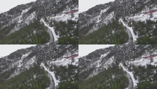 在冬天，汽车在雪山中行驶。在被绿色森林包围的雪山上飞行。山间的山路高清在线视频素材下载