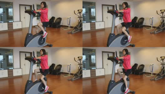 微笑的女人在健身房里做动感单车运动高清在线视频素材下载