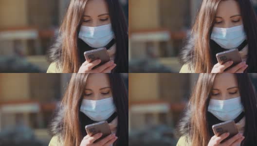 一名妇女戴着防空气污染和冠状病毒的医用口罩，在城市街道上用手机打字高清在线视频素材下载