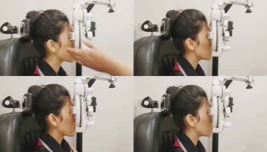 一名年轻女子在眼科诊所用透视仪检查她的眼睛高清在线视频素材下载