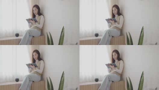 年轻的亚洲女性在家里用数码平板电脑工作高清在线视频素材下载