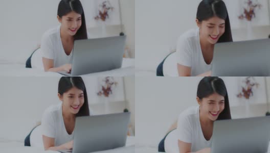 亚洲年轻女性在电脑上打字放松，看社交媒体上的热门视频，和朋友在卧室聊天。有吸引力的女性躺在床上玩和使用笔记本电脑应用程序。高清在线视频素材下载