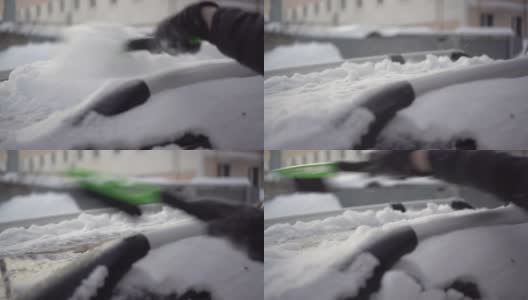 一名男子用刷子清理车顶上的积雪。汽车被雪覆盖着。天气灾害。4 k高清在线视频素材下载